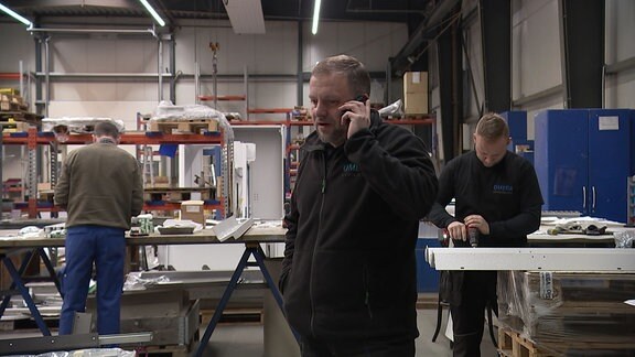 Ein Mann telefoniert in einer Werkstatt.