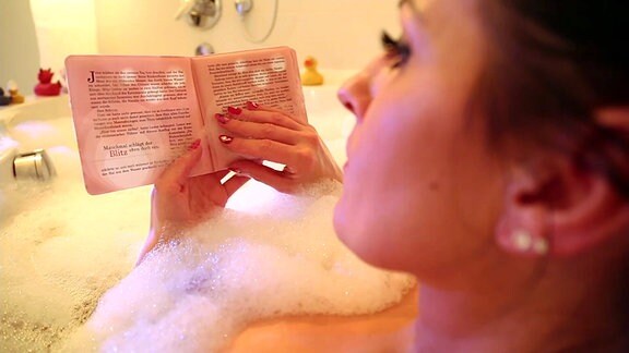 Frau beim Lesen eines Badebuches in der Wanne