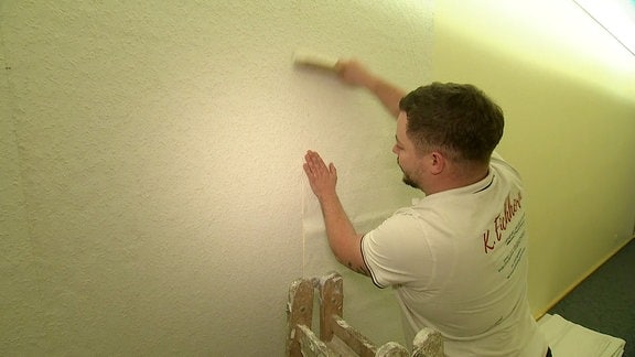 ein Mann tapeziert eine Wand