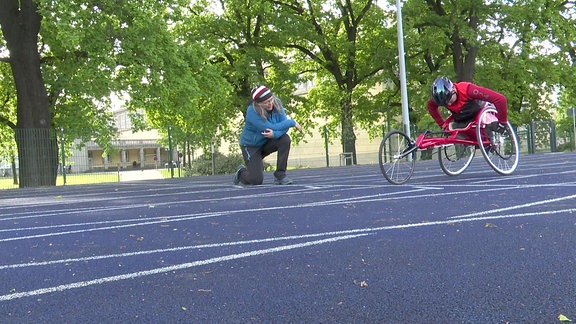 Eine Frau und ein Rollstuhlfahrer auf der Rennstrecke