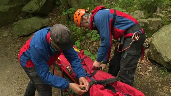 Zwei Bergretter im Harz bereiten eine Rettungstrage vor.