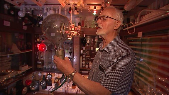 Siefried Blesch hält eine überdimensionale Glühbirne in der Hand.