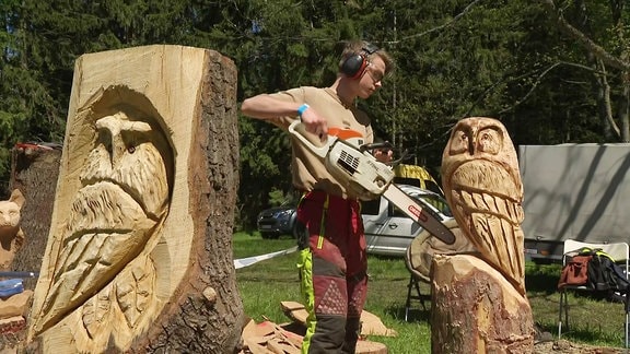 Ein junger Mann macht mit einer Motorsäge eine Holzskulptur
