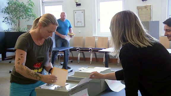 Menschen bei der Stimmabgabe im Wahlbüro