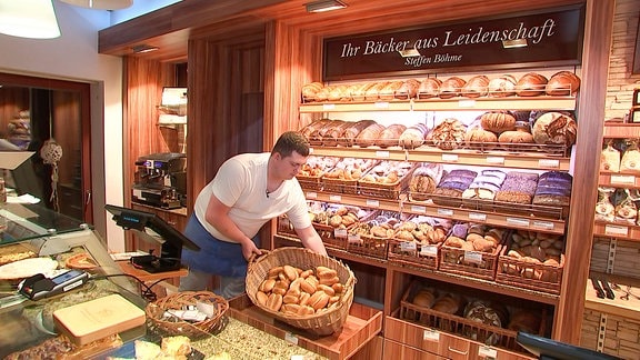 Ein Bäcker trägt einen Korb mit Brötchen