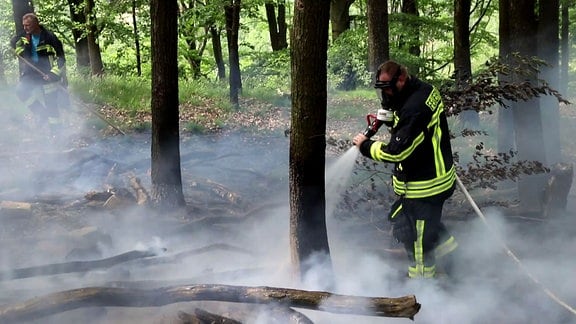 Feuerwehr löscht Glutnester am Waldboden.