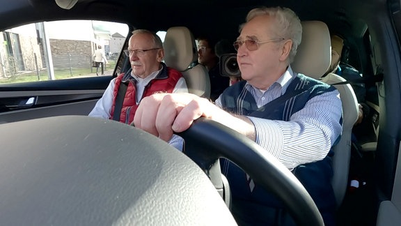 Zwei ältere Herren sitzen in einem Auto.