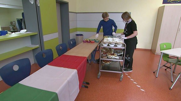 Schüler stellen Essen auf einer Tafel bereit.