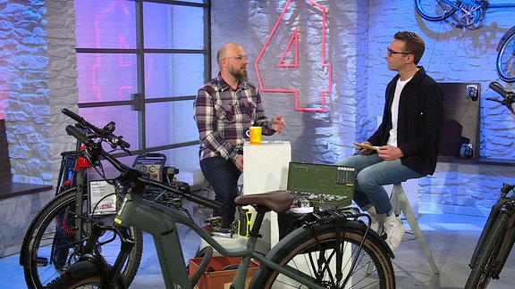 David Koßmann im Studio während Gespräch mit Moderator Peter Imhof, im Vordergrund stehen E-Bikes.