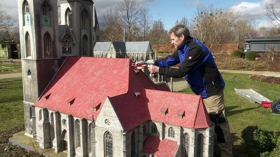 Ein Mann arbeitet an einem Model einer Kirche.
