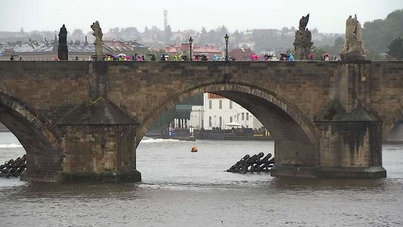 Menschen mit Regenschirmen auf der Karlsbrücke.