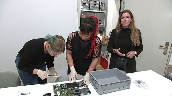 Frauen zerlegen einen Laptop um an den Datenträger zu gelangen.