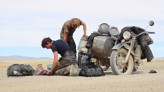 Menschen neben einem Motorrad in der Wüste