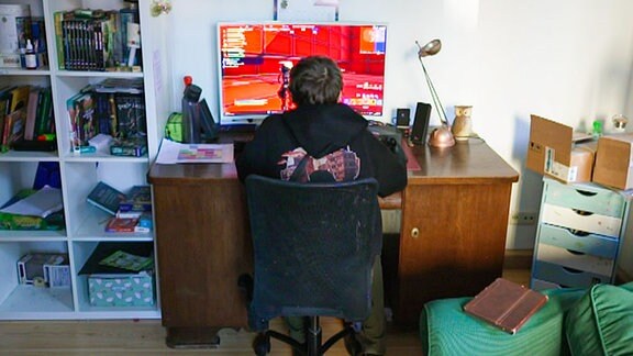 Ein Kind sitzt in seinem Zimmer am PC
