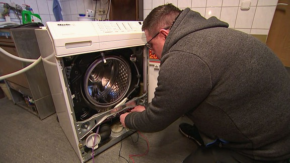Ein Mann baastelt an einer Waschmaschine