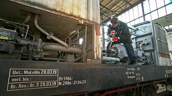 Ein Mitarbeiter der Bahnwerkstatt Benndorf werkelt an einer Lok