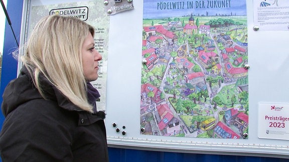 Eine Frau schaut auf eine gemalte Karte eines Dorfes