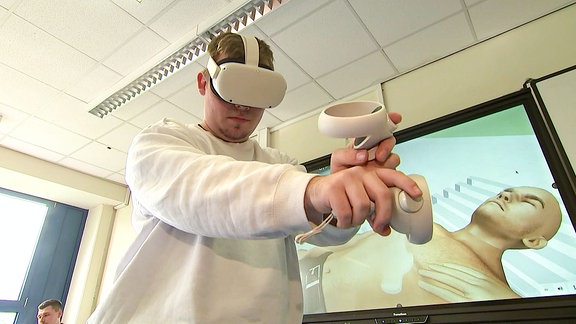 Ein Schüler mit einer VR Brille, im HIntergrund ist ein animierter Mann zu sehen
