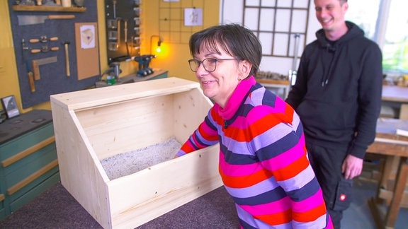 Eine Frau greift in eine Holzkiste