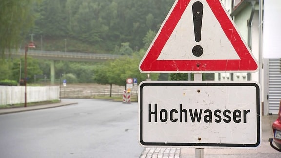 An einer Straße ist ein Gefahrenschild für Hochwasser