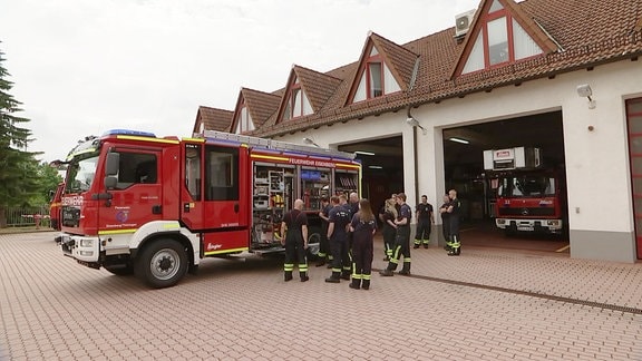 Neues Feuerwehrfahrzeug vor dem Einsatzgebäude mit Feuerwehrkräften