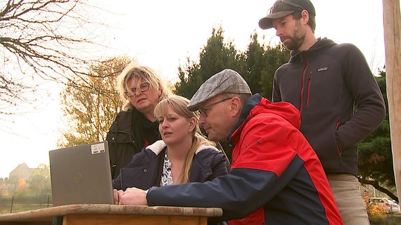 Vier Menschen schauen auf einen Laptop