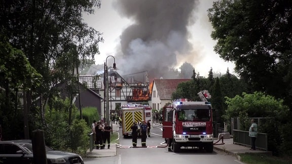 Feuerwehrfahrzeuge vor brennendem Haus