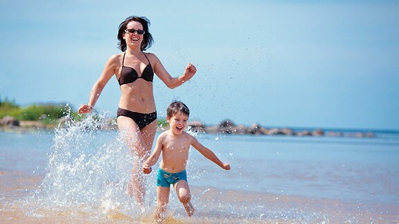 Eine Frau und ein Junge rennen am Strand