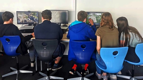 Mehrere Kinder sitzen nebeneinander vor Computern und spielen Videospiele.
