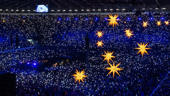 Besucher leuchten 2019 mit ihren Handys während Mitglieder des Dresdner Kreuzchors und der Dresdner Kapellknaben beim fünften Adventskonzert im Rudolf-Harbig-Stadion singen.