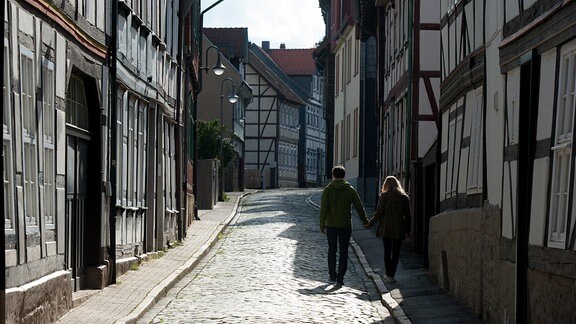 Ein Pärchen geht 2015 in Goslar durch eine Straße mit Fachwerkhäusern.