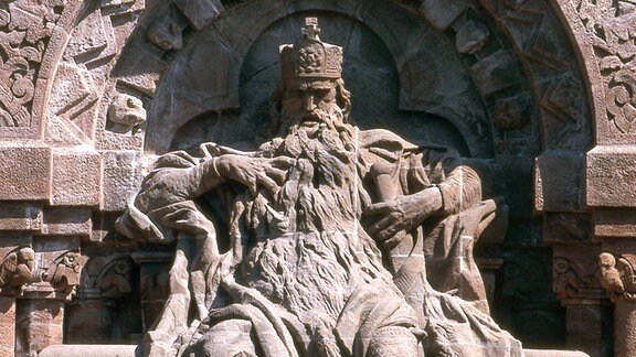 Steinskulptur eines als Barbarossa bekannten Mannes mit Krone und wallendem Bart, der auf einem Thron sitzt.