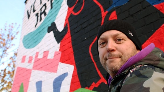 Alexander Lech vor einer Wand mit Graffiti