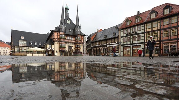 Marktplatz in Wernigerode ist zu sehen, im Hintergrund sieht man Fachwerkhäuser, vorn ist eine große Pfütze mit Spiegelung, da es geregnet hat