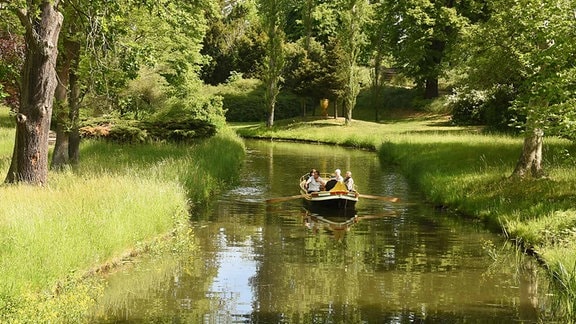 Eine Gondel fährt mit Besuchern auf den weit verzweigten Kanälen vor dem Gotischen Haus im Wörlitzer Park entlang