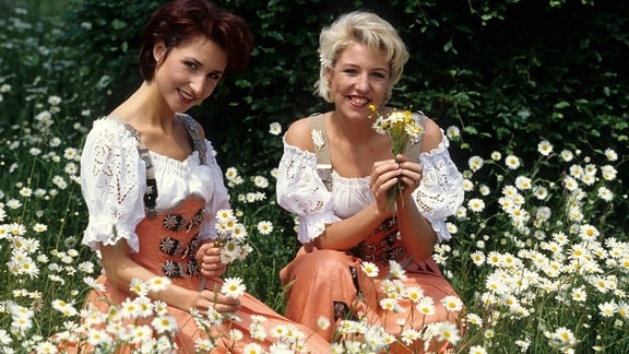 Anita (li.) und Alexandra Hofmann (beide Geschwister Hofmann) auf einer Blumenwiese