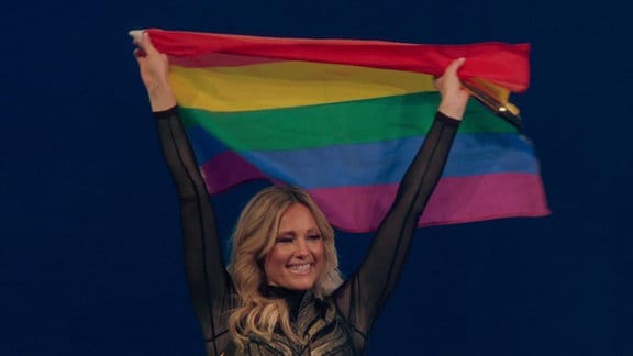 Helene Fischer hebt während eines Auftritts eine Regenbogenflagge in die Höhe.