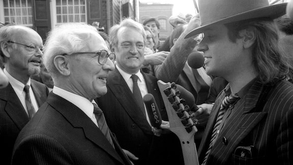 Sänger Udo Lindenberg (re.) überreicht Erich Honecker (DDR/Staatsratsvorsitzender) im Beisein von Johannes Rau (Mitte, BRD/SPD/Ministerpräsident NRW) eine Gitarre in Wuppertal