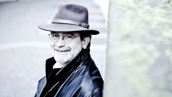 Dirigent Andrea Marcon lächelnd mit Hut auf der Straße