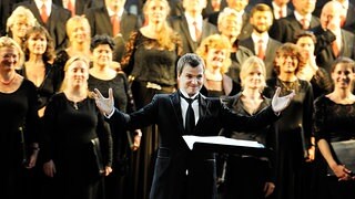 Vor dem MDR RUNDFUNKCHOR steht Risto Joost mit ausgebreiteten Armen und lächelt. | Bildrechte: MDR/Christiane Fritsch Vor dem MDR RUNDFUNKCHOR steht Risto Joost mit ausgebreiteten Armen und lächelt.