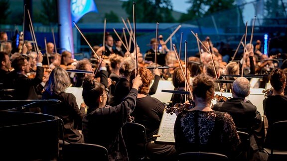 Die Streicher des MDR-Sinfonieorchesters beim Schlussakkord des Konzerts "Carmina Burana" im MDR-Musiksommer auf der Seebühne im Magdeburger Elbauenpark. 