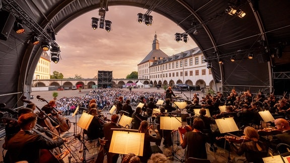 Blick von hinten über die Bühne: MDR-Sinfonieorchester und Dennis Russell Davies beim Eröffnungskonzert des MDR-Musiksommers 2023 im Innenhof von Schloss Friedenstein in Gotha