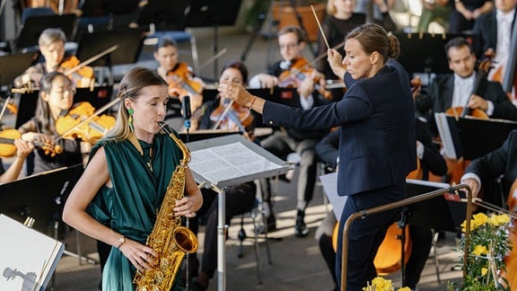 Lucie Lequay dirigiert Saxophonistin Valentine Michaud und das MDR-Sinfonieorchester beim Eröffnungskonzert des MDR-Musiksommers 2024 im Sangerhausen. 