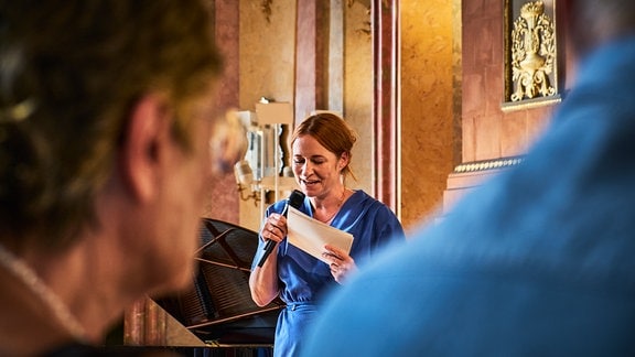 MDR KULTUR-Literaturredakteurin Katrin Schumacher spricht im blauen Kleid mit Mikrofon vor Publikum auf der Heidecksburg