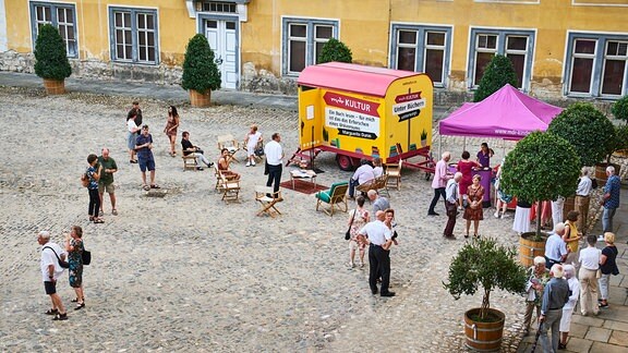 Der gelbe Bücherwagen von MDR KULTUR im Hof der Heidecksburg mit verstreuten Konzertbesuchern