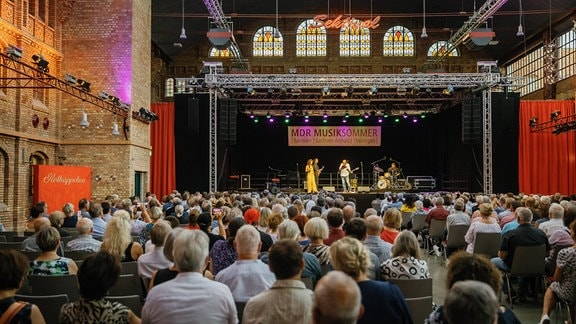 Nils Landgren sowie Alma Naidu und Band auf der Bühne beim Konzert in der Rotkäppchen Sektkellerei in Freyburg mit Publikum von hinten 
