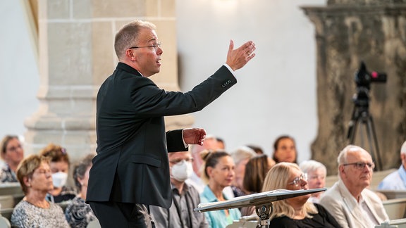 Philipp Ahmann dirigiert den MDR-Rundfunkchor im Konzert beim MDR-Musiksommer 2024 in Torgau