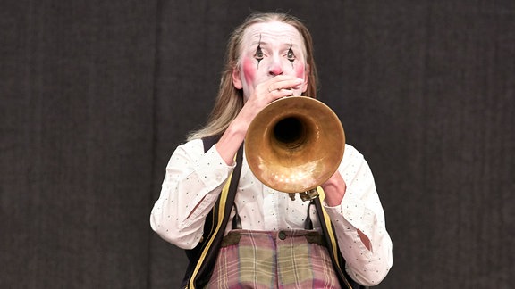 Ein Mitglied des Blechblas-Ensembles Mnozil Brass hat sich als trauriger Clown verkleidet und sitzt auf der Bühne im Naturtheater Bad Elster beim MDR MUSIKSOMMER.