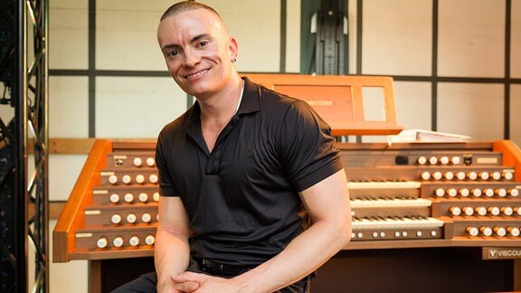 Cameron Carpenter lächelnd am Spieltisch seines Orgeltrucks beim Eröffnungskonzert der MDR-Musiksommer Sonderausgabe in Erfurt