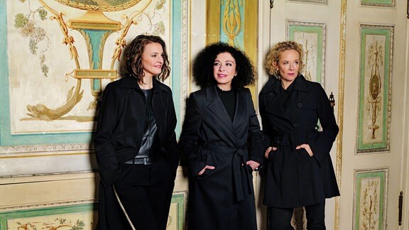 Katja Riemann, Franziska Hölscher und Marianna Shirinyan stehen zu dritt vor einer Wand